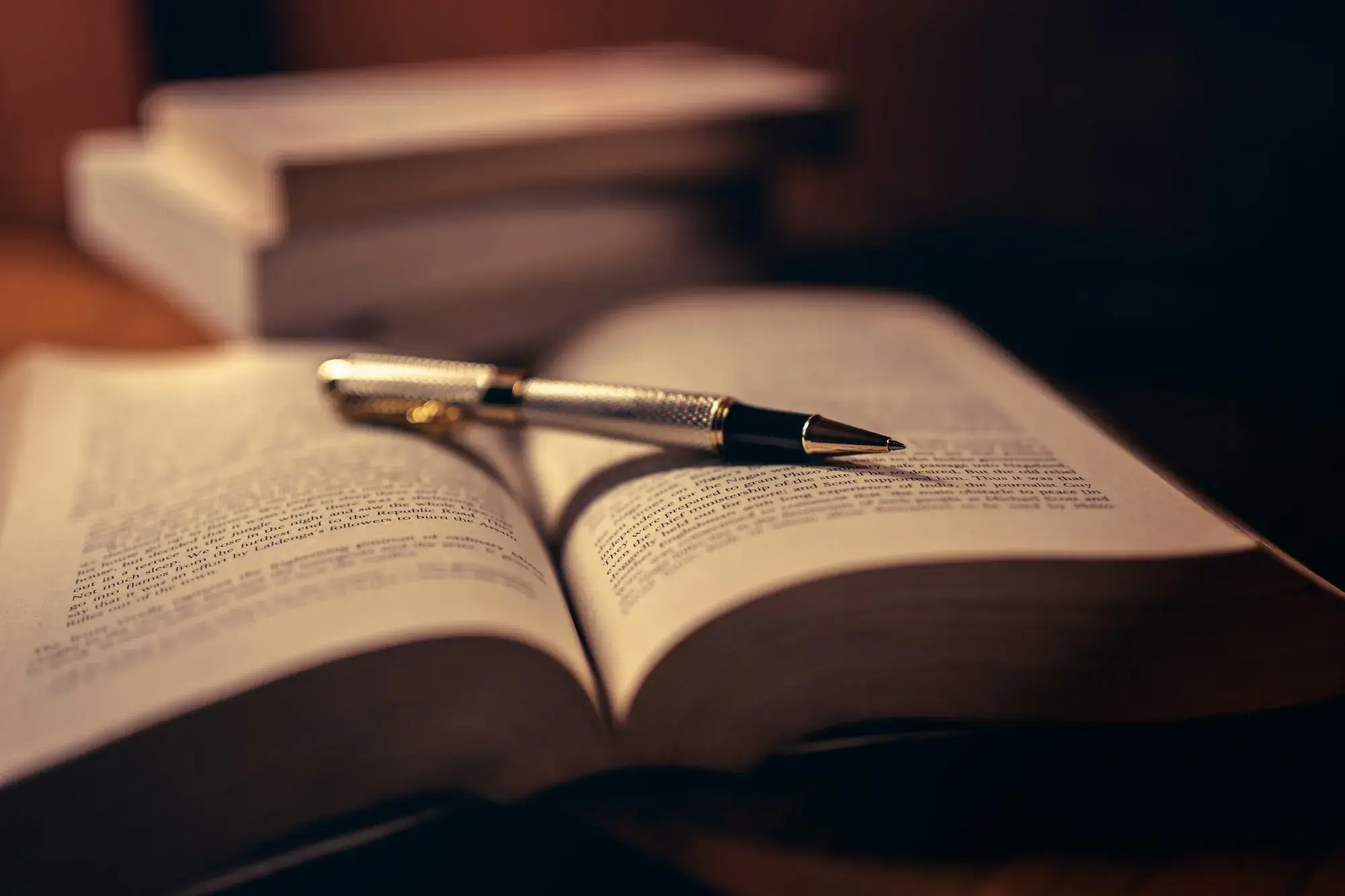 Penna appoggiata sulle pagine di un libro aperto in luce calda
