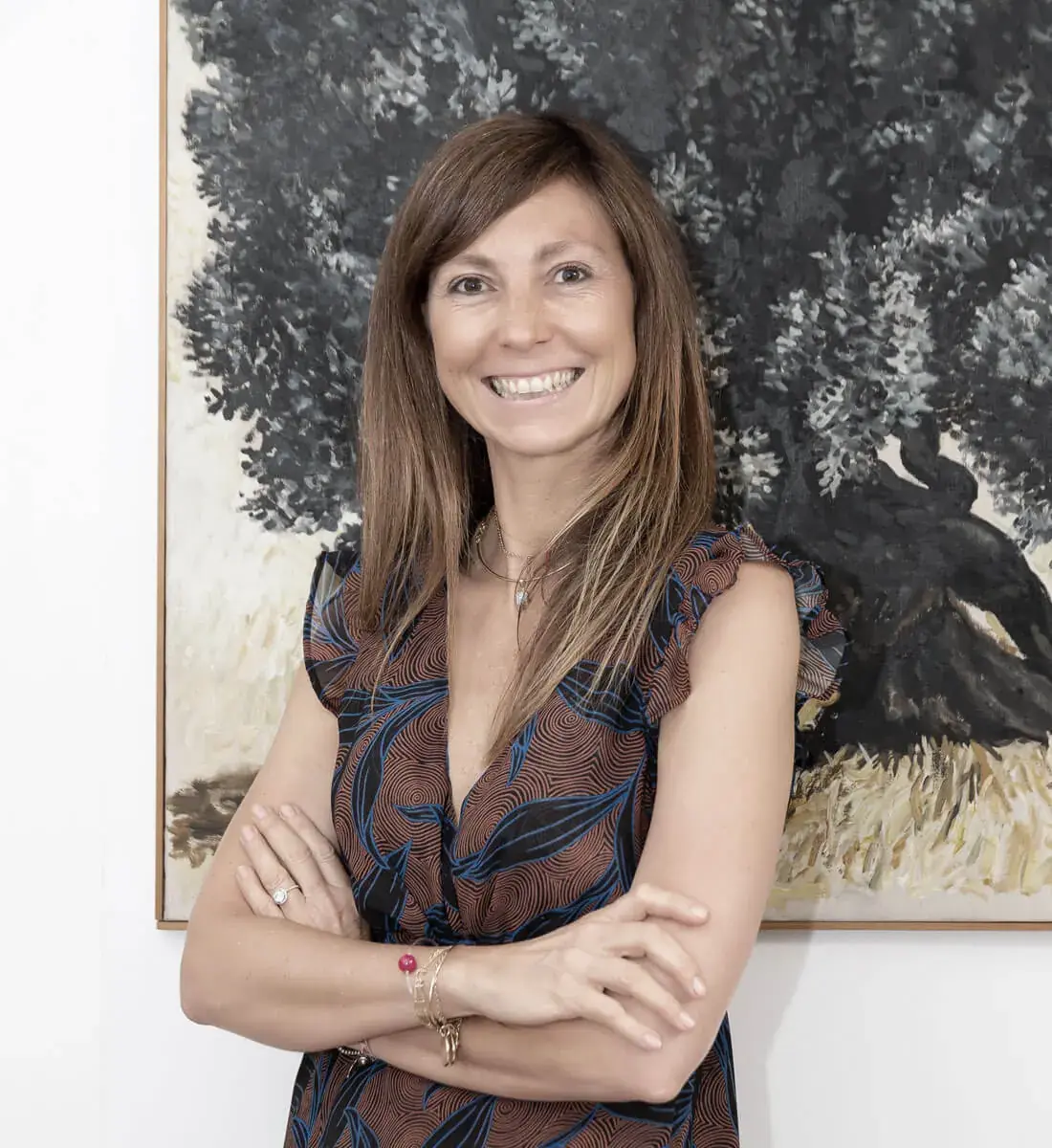L'avv. Lisa Armenio sorridente davanti a un dipinto con un grande ulivo