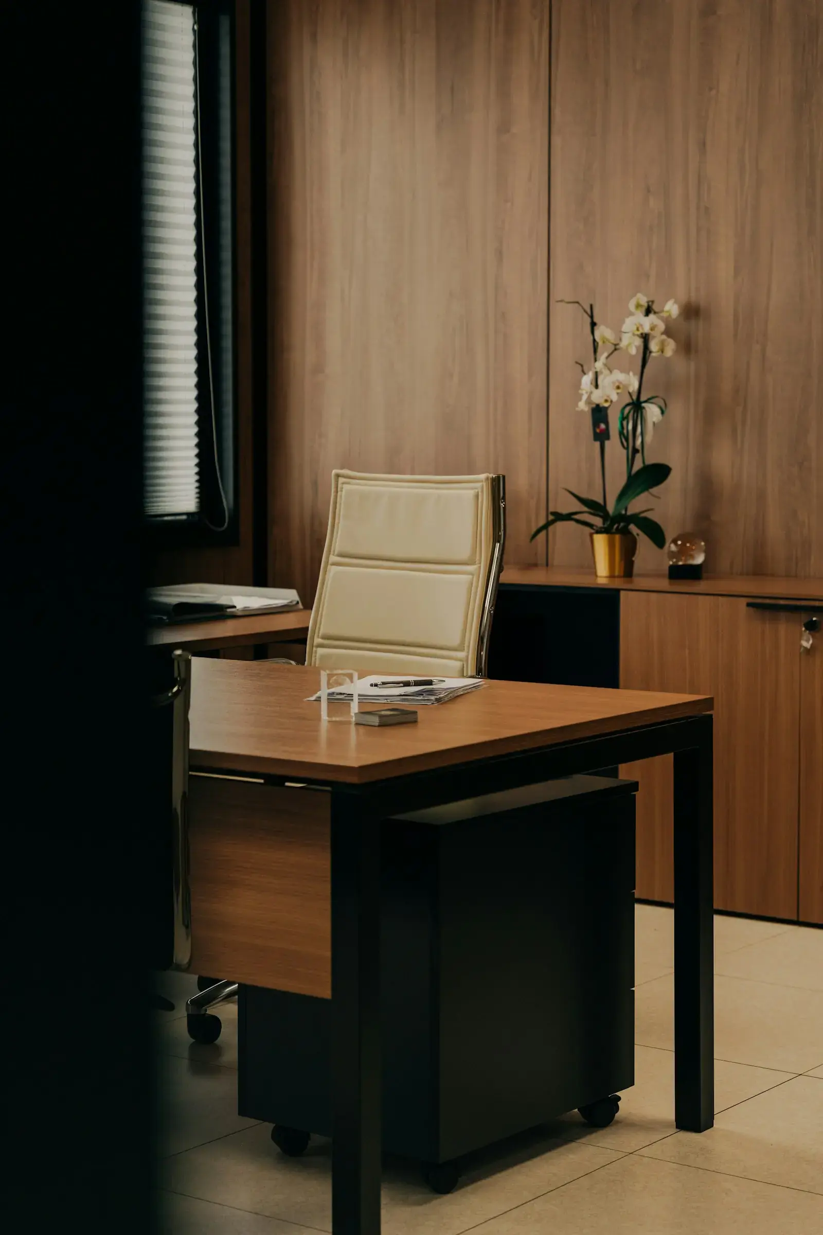 Interno di uno studio professionale con scrivania in legno, poltrona e pareti rivestite in legno caldo